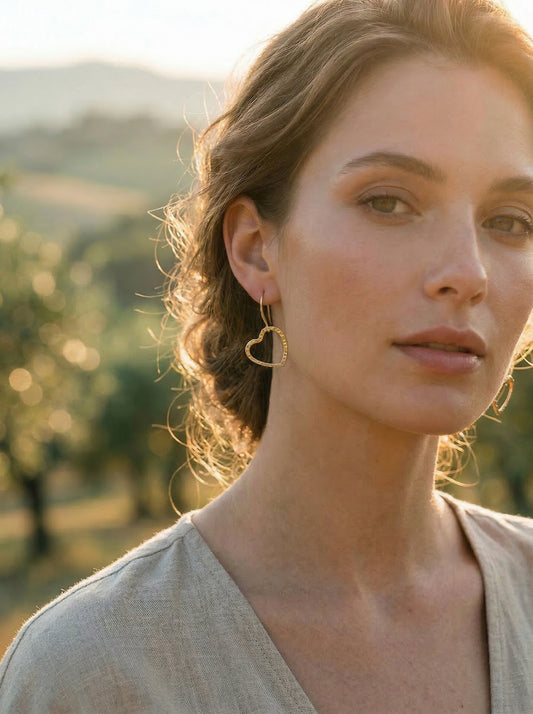Woman with gold heart-shaped earrings in a natural setting