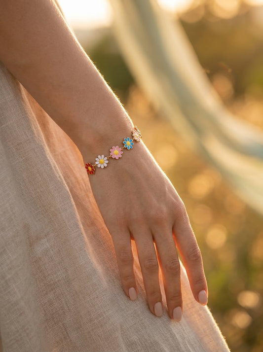 Hand wearing a multicoloured daisy bracelet with a blurred natural background
