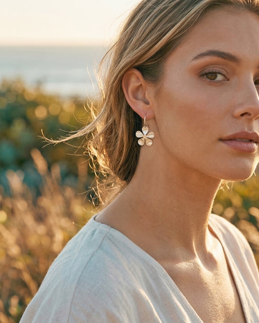 Woman wearing a silver flower earring in a natural setting
