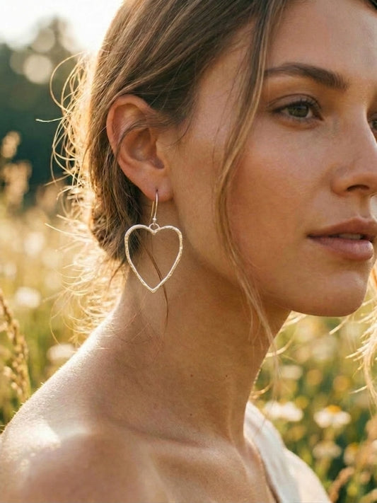 Woman wearing silver heart-shaped earrings in a natural setting