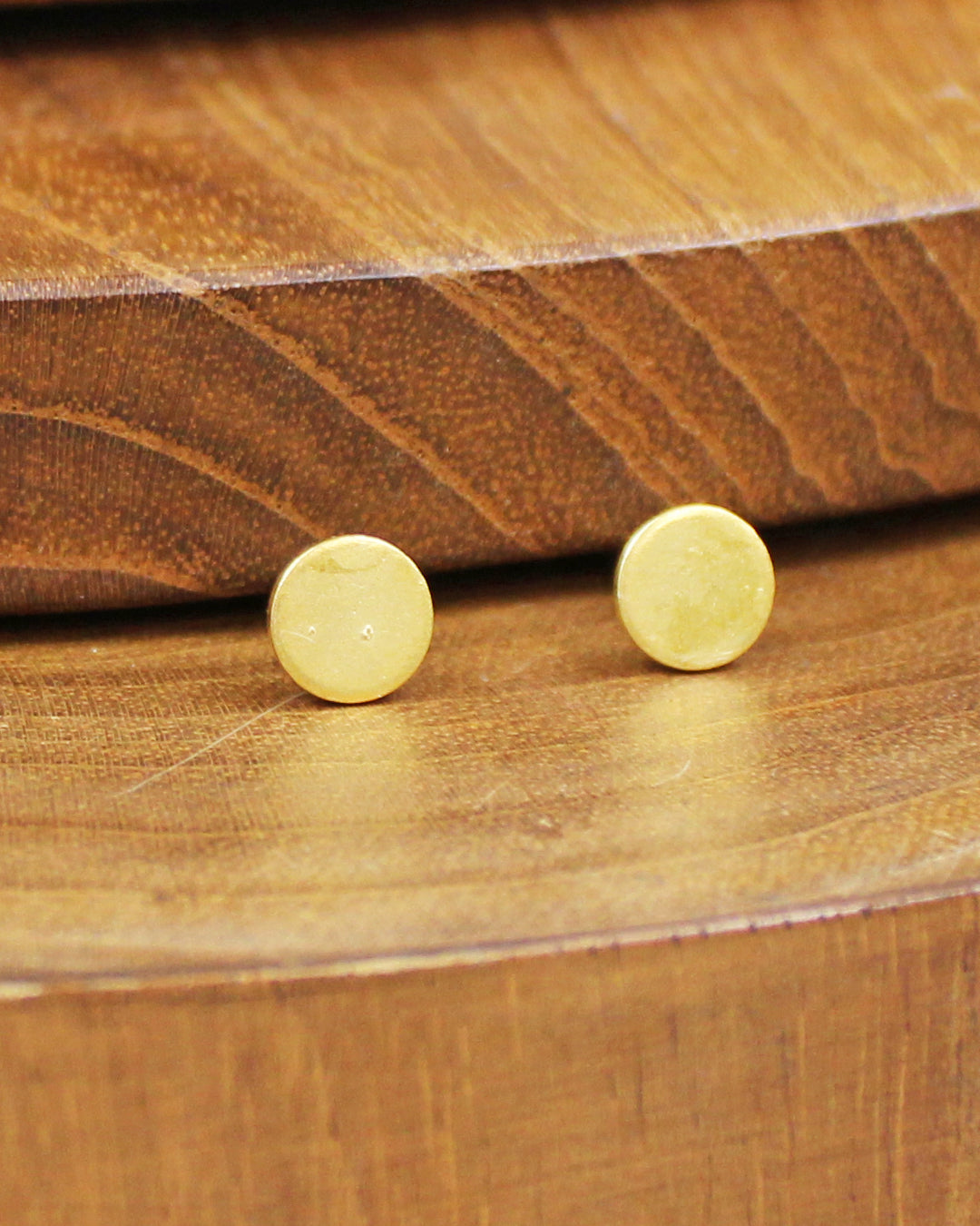 Gold stud earrings on a wooden surface