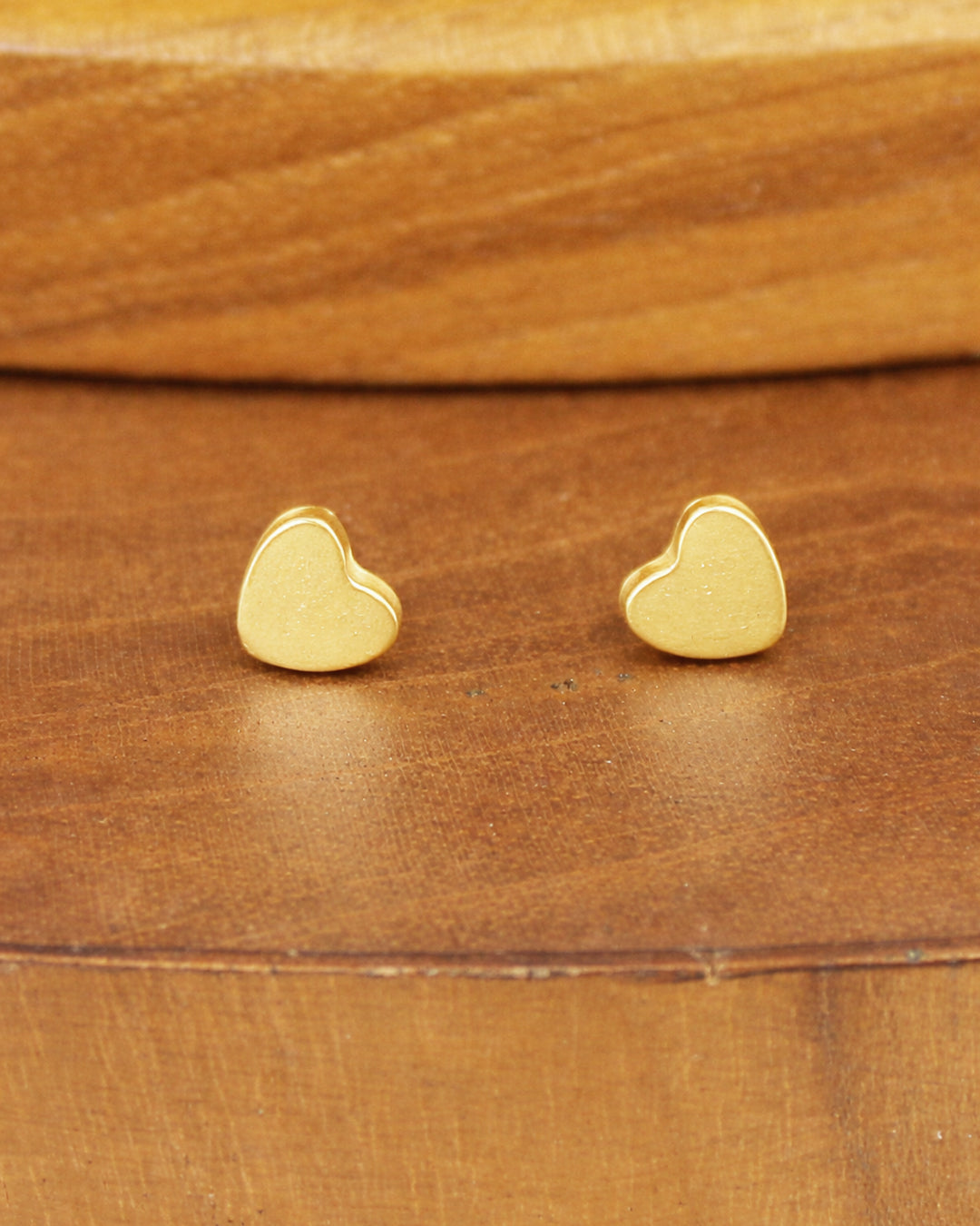 Gold heart-shaped earrings on a wooden surface