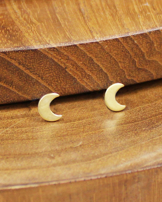 Gold crescent moon earrings on a wooden surface