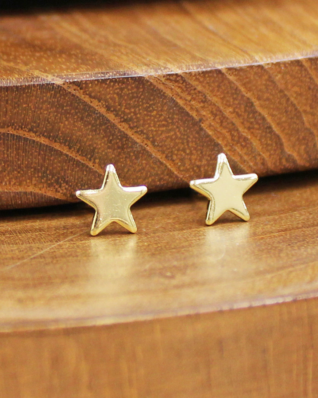 Gold star earrings on a wooden surface