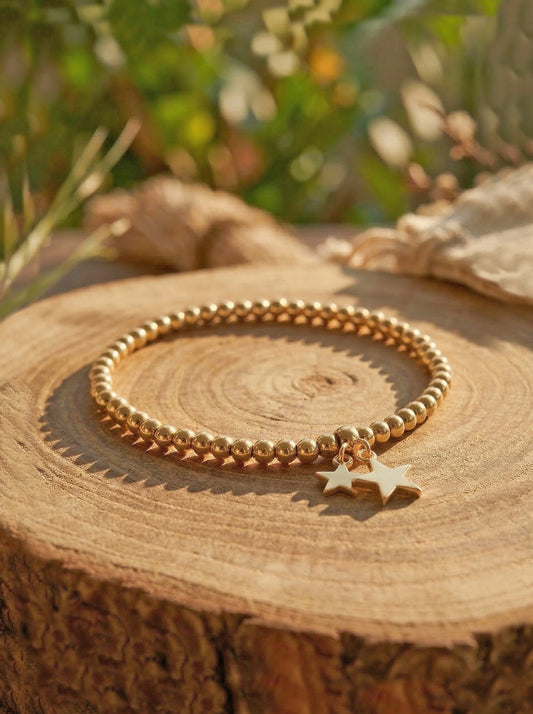 Gold bracelet with star charm on a wooden surface