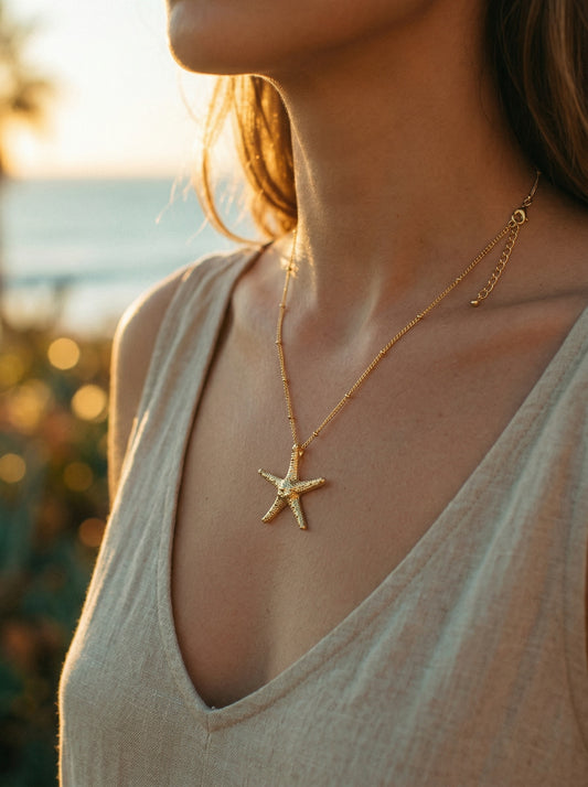 Woman wearing a gold starfish necklace with a blurred natural background at golden hour