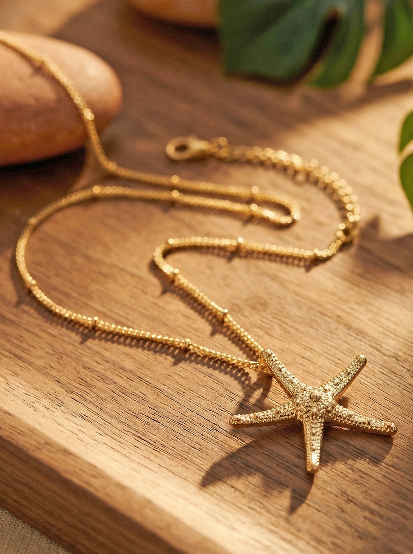 Gold realistic starfish pendant necklace on a wooden surface