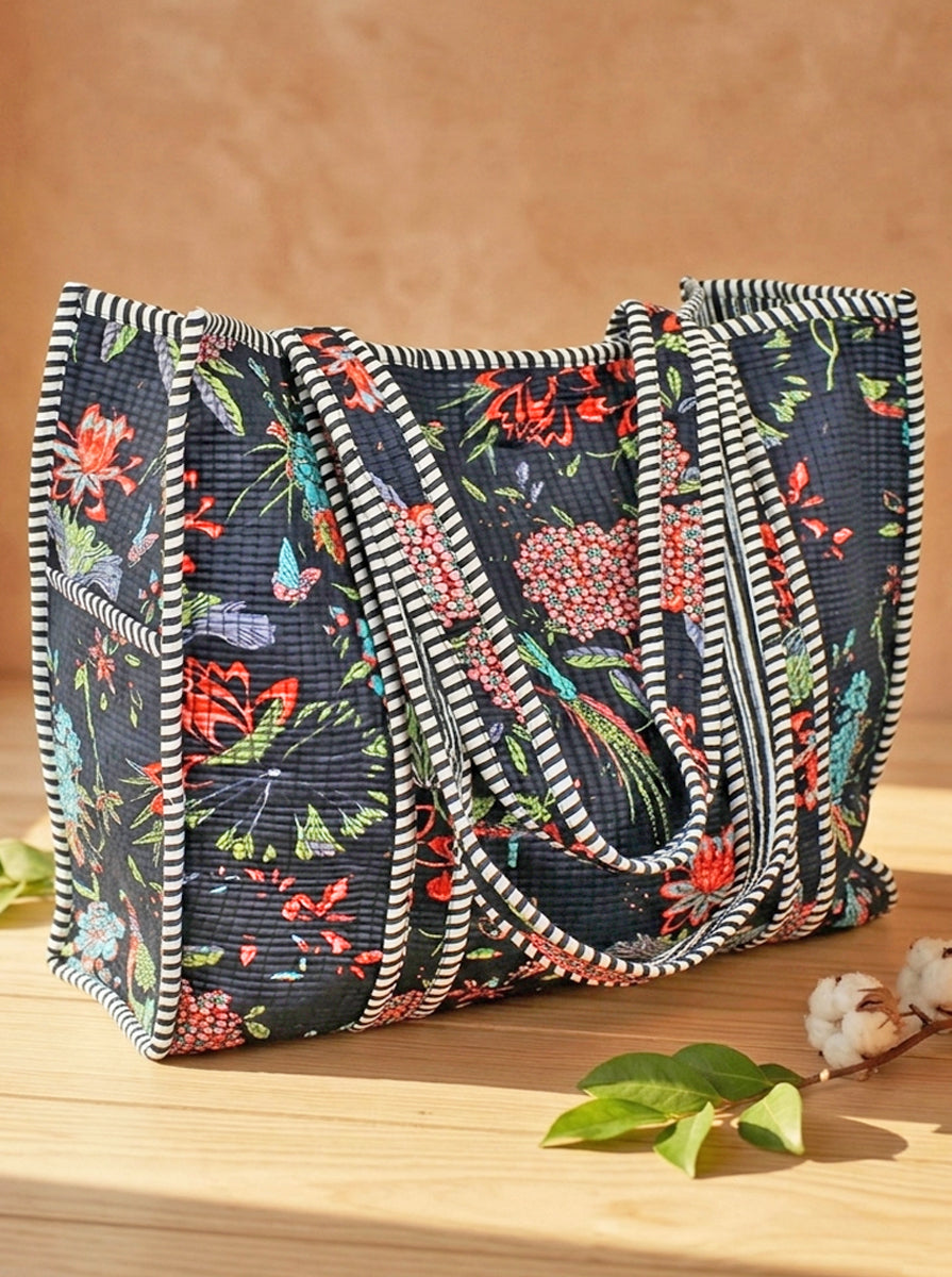 Floral-patterned quilted cotton tote bag with striped edges on a wooden surface