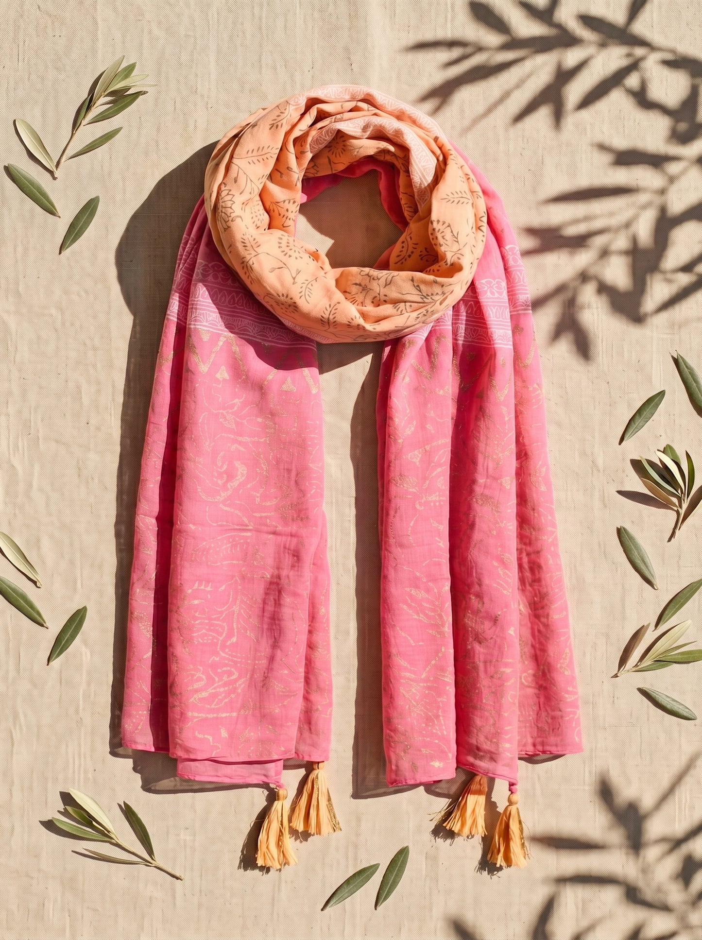 Pink & orange block printed scarf with tassels on a beige background with leaf shadows