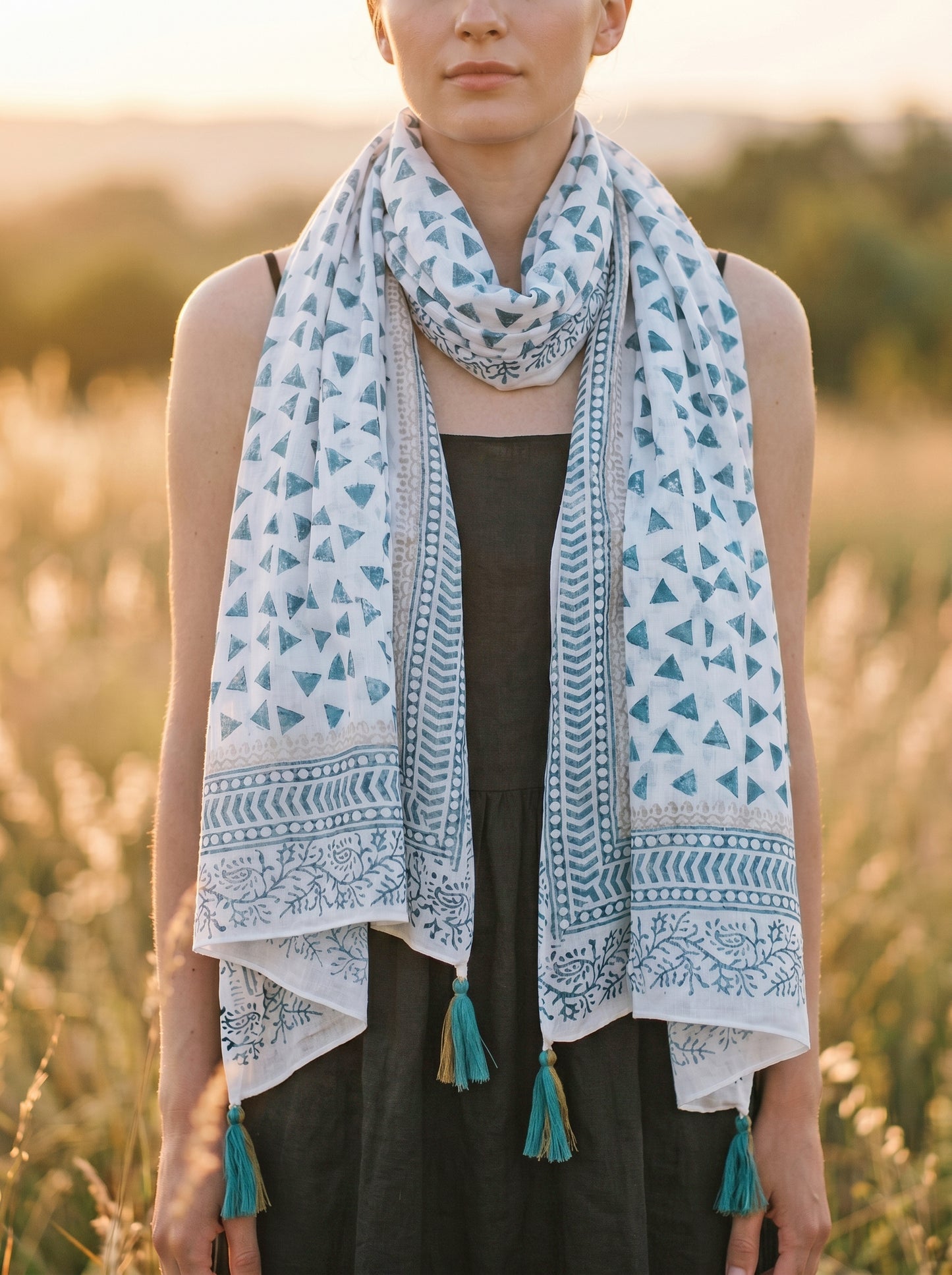 Woman wearing a patterned scarf with tassels in a natural setting
