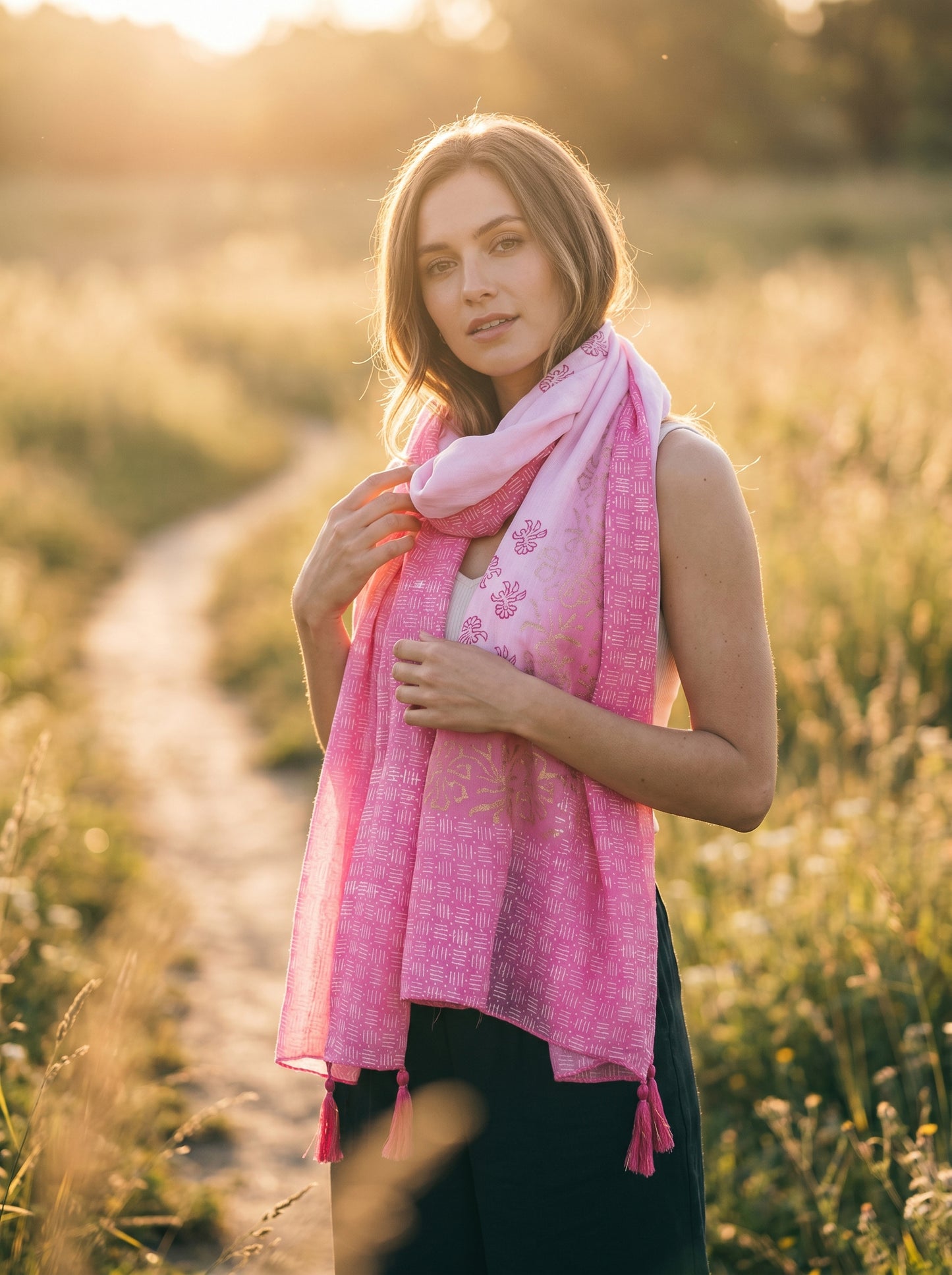 Woman wearing a pink scarf in a field with a blurred background