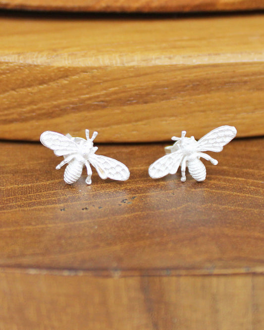 Silver bee-shaped earrings on a wooden surface