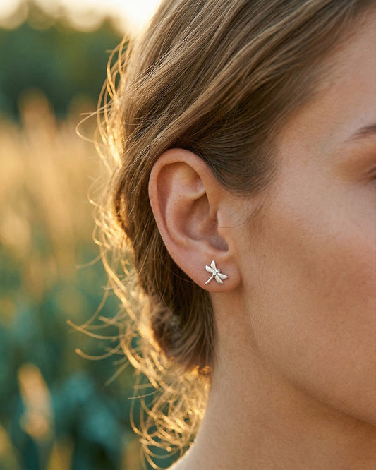 Women wearing silver dragonfly shaped earrings in a natural setting