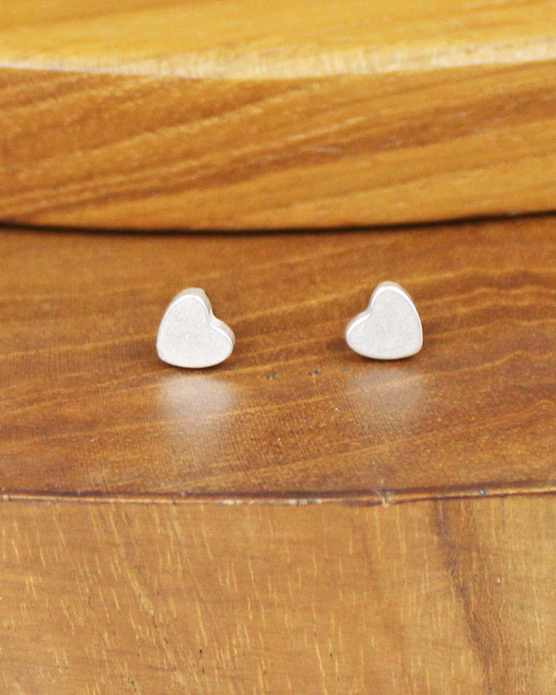 Heart-shaped silver earrings on a wooden surface