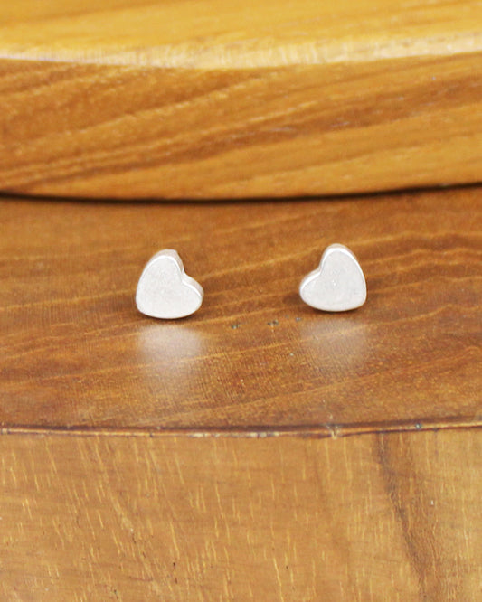 Heart-shaped silver earrings on a wooden surface