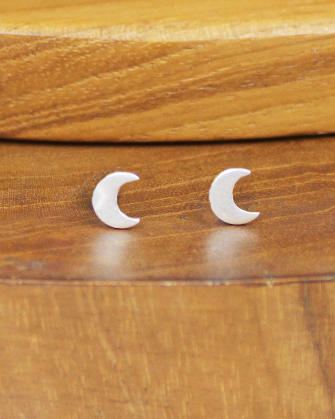 Pair of silver moon shaped earrings on a wooden background