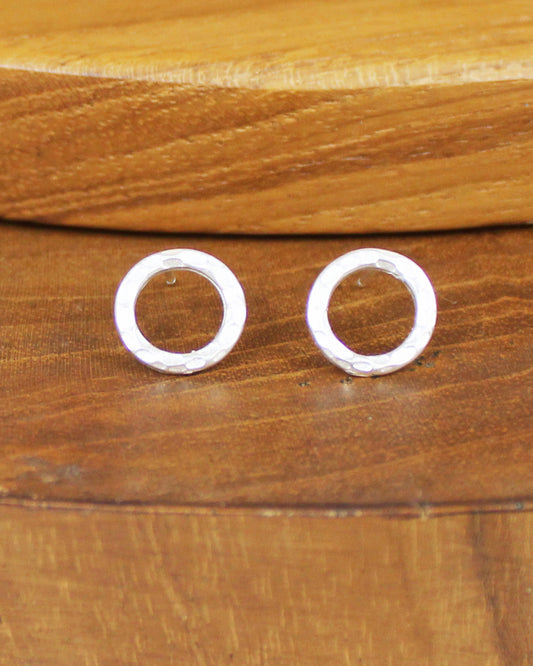 Pair of silver circular earrings on a wooden surface