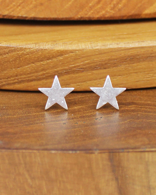 Silver star-shaped earrings on a wooden surface