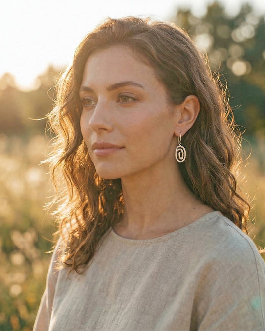 Woman wearing silver swirl earrings with a blurred natural background