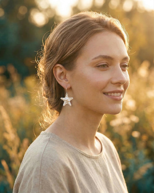 Woman wearing silver star-shaped earrings in a natural setting
