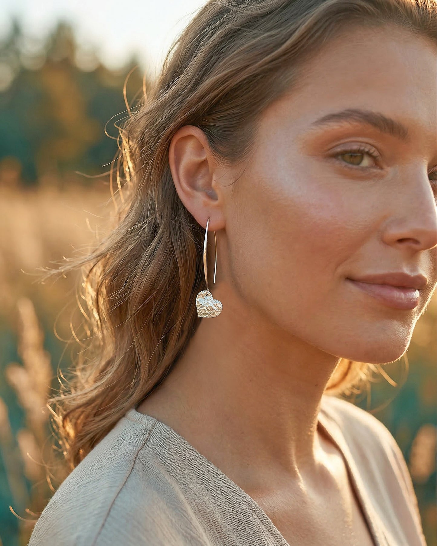 Woman wearing silver heart earrings with a blurred natural background