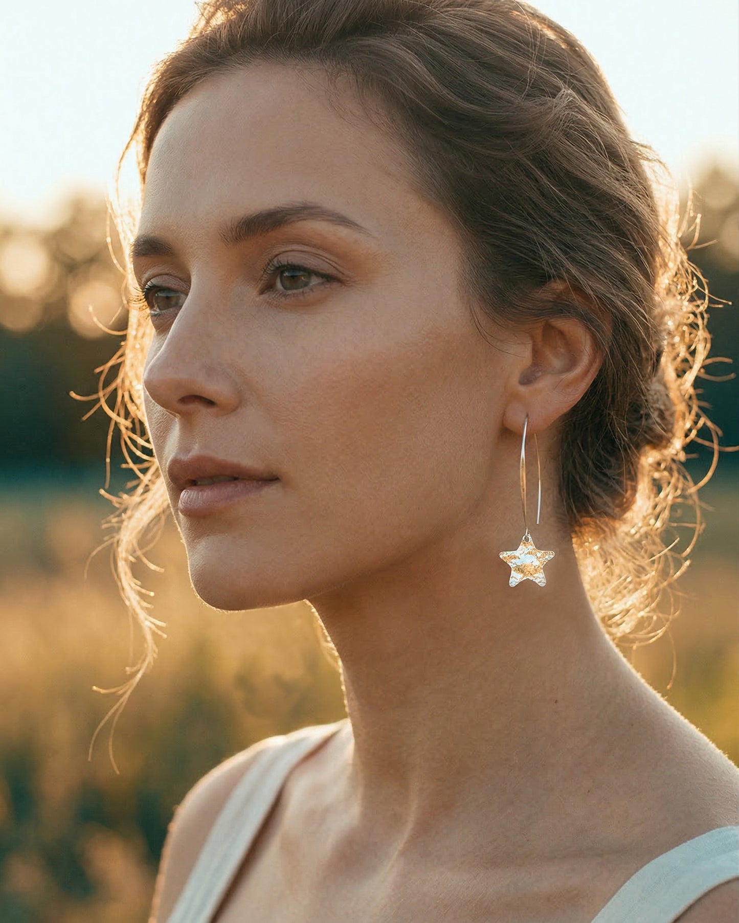 Woman wearing silver star-shaped earrings with a blurred natural background