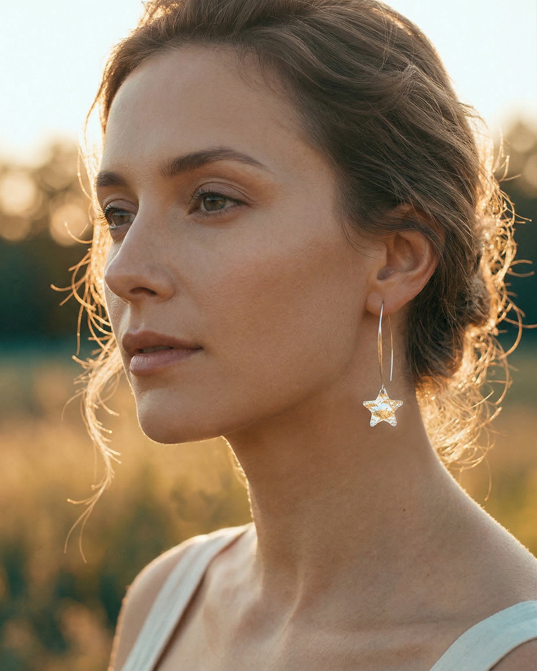 Woman wearing silver star-shaped earrings with a blurred natural background