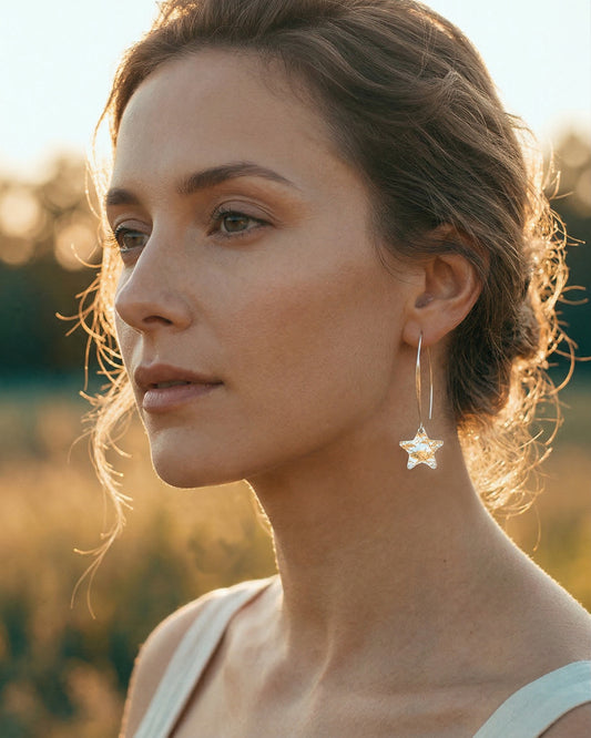 Woman wearing silver star-shaped earrings with a blurred natural background