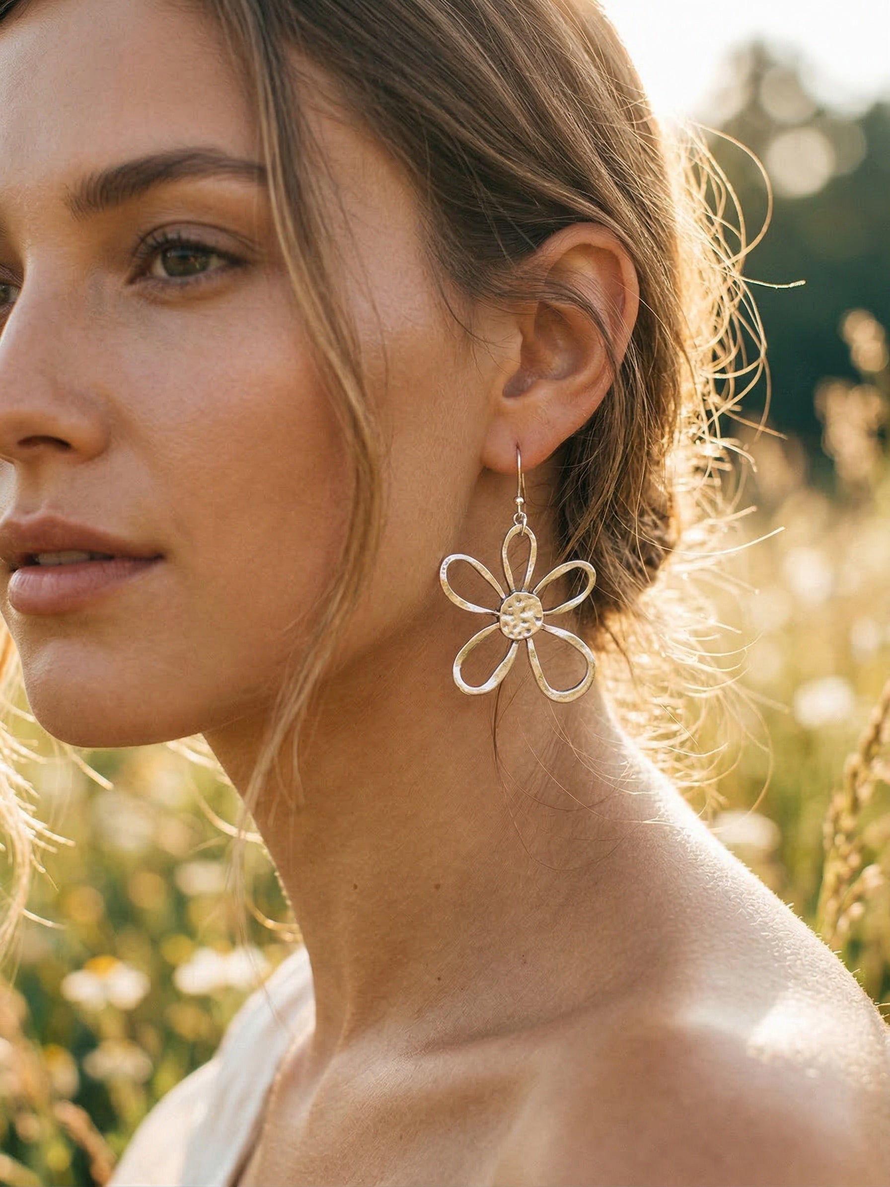 Woman wearing a large daisy earring in a natural setting